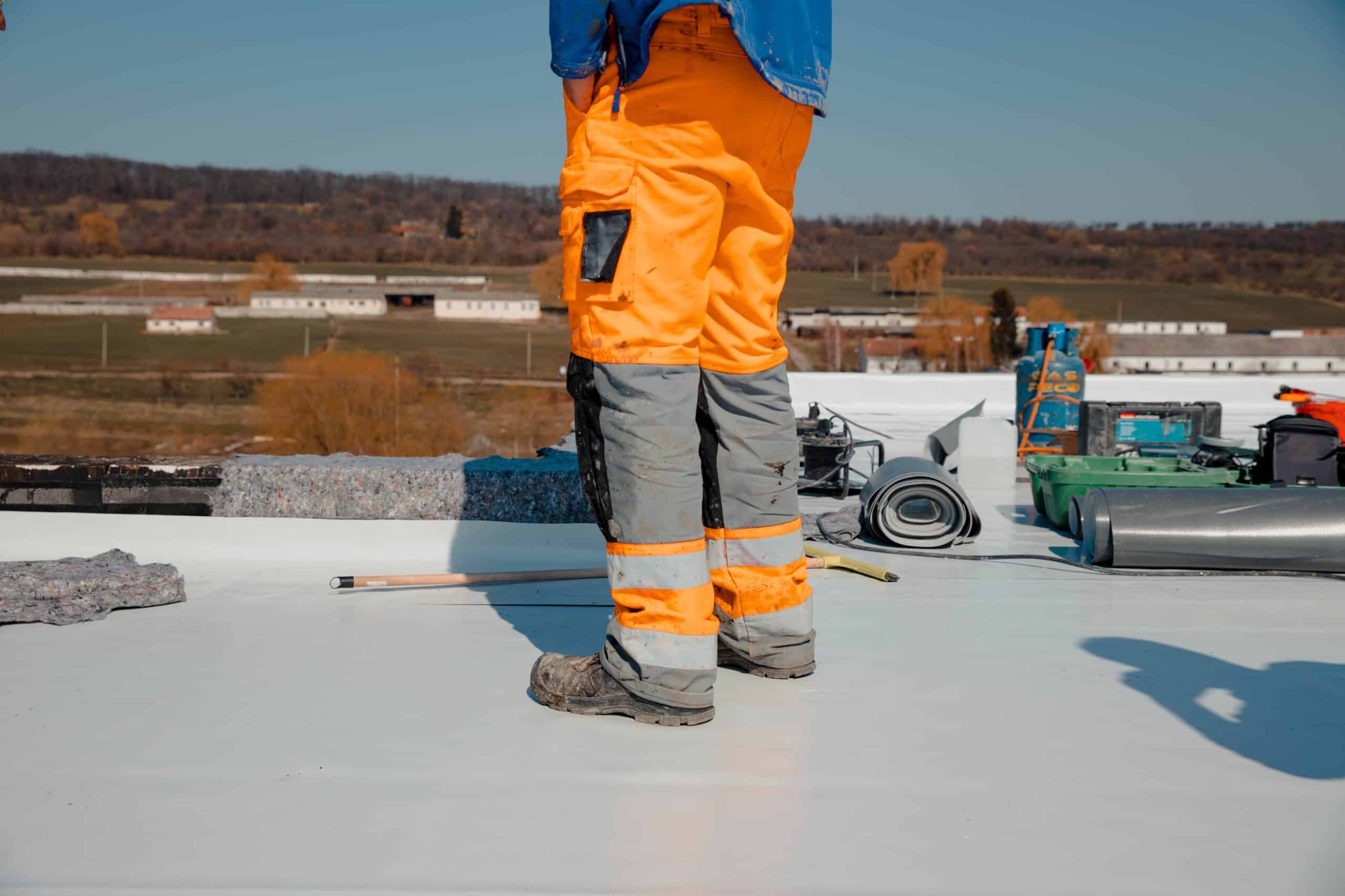 - King Energy Roofer man does commercial roofing work on a flat roof with pvc membrane insulation system